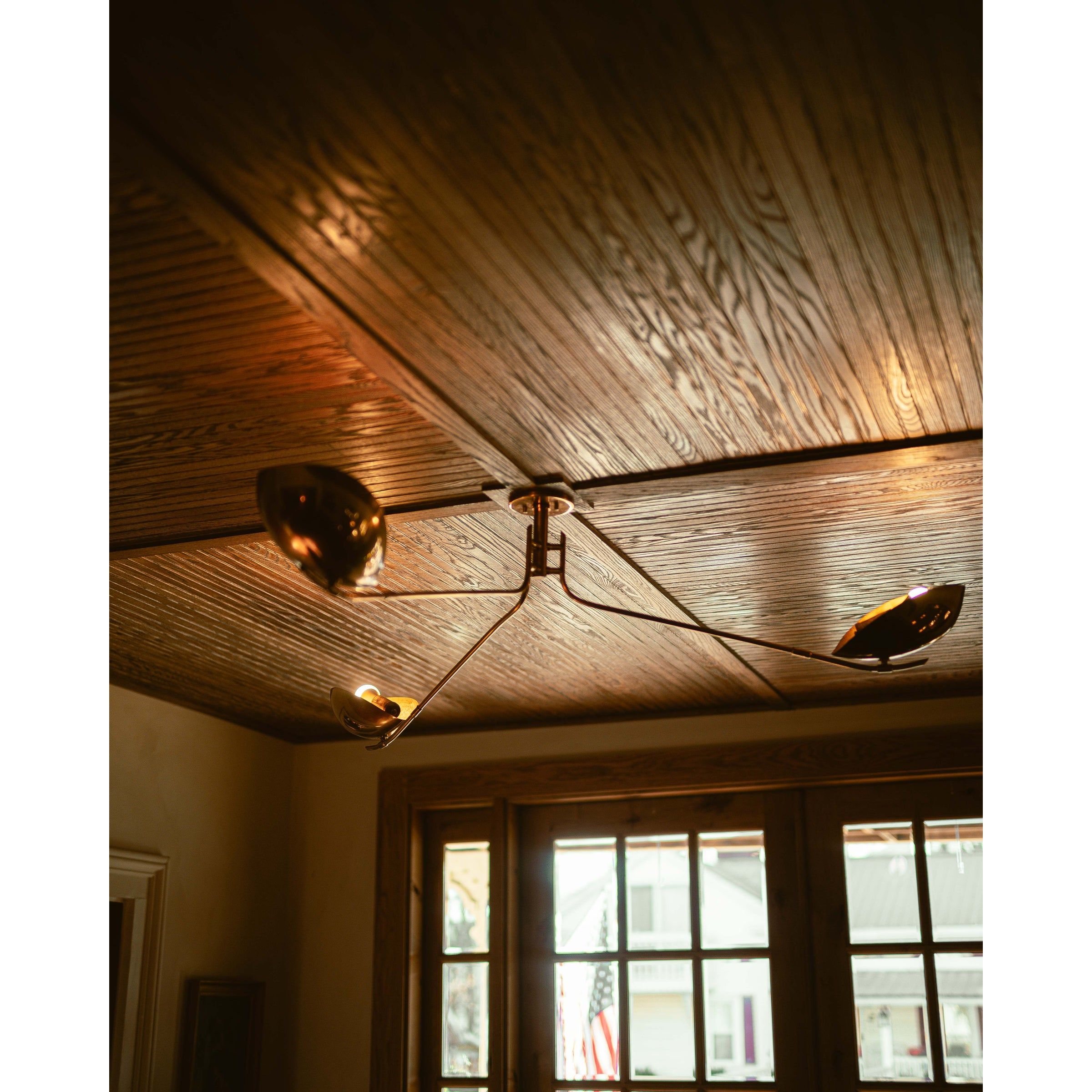 Avondale multi-arm ceiling light with dark bronze finish installed on rustic wooden plank ceiling with windows below