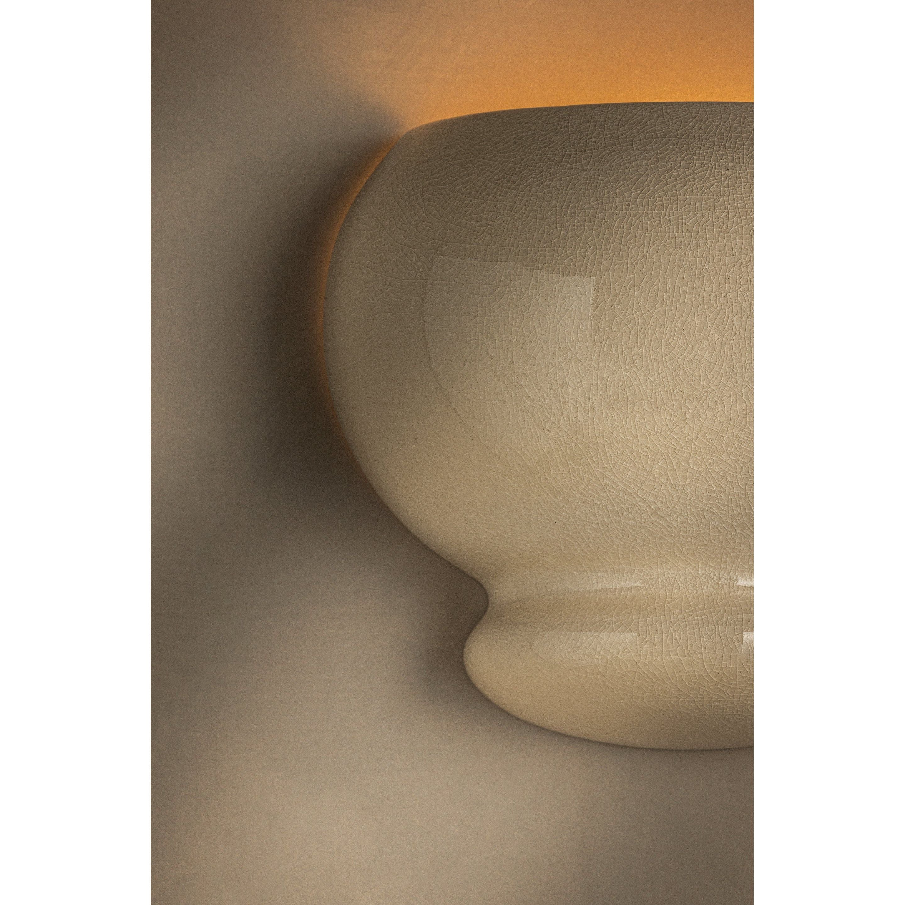 Close-up detail of cream ceramic bubble wall sconce showing textured surface with warm amber glow