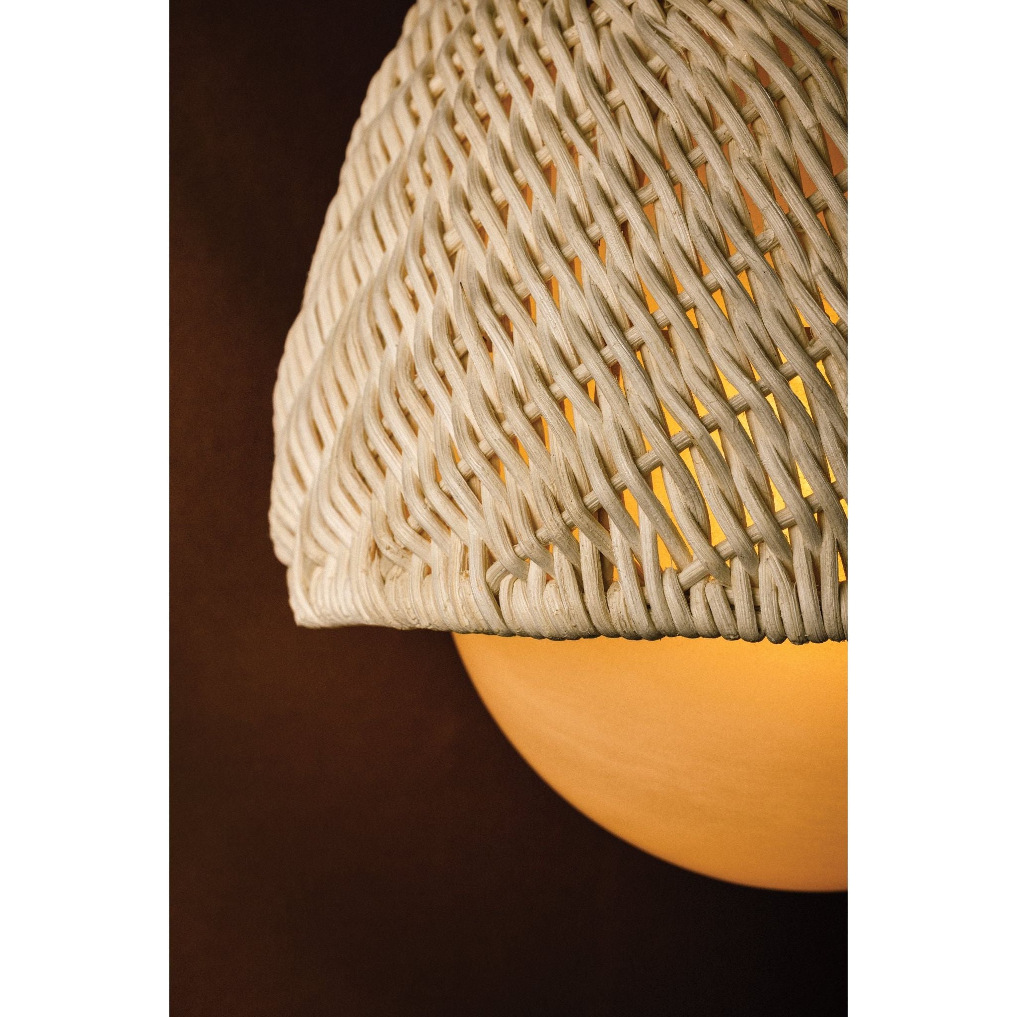 Close-up detail of Piasu wall sconce woven rattan shade showing intricate woven texture with warm amber glow from within