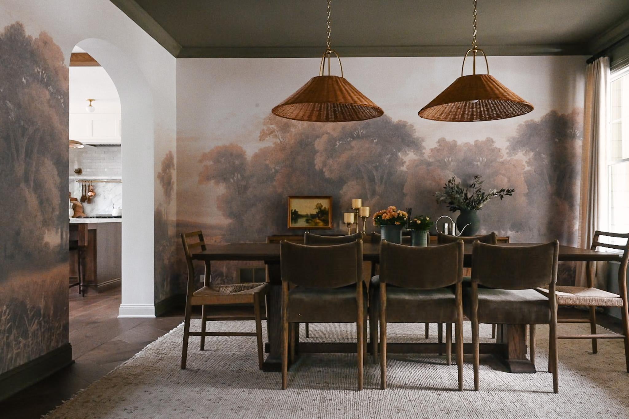 Two Davida pendant lights in aged gold brass hanging over a rustic dining room table
