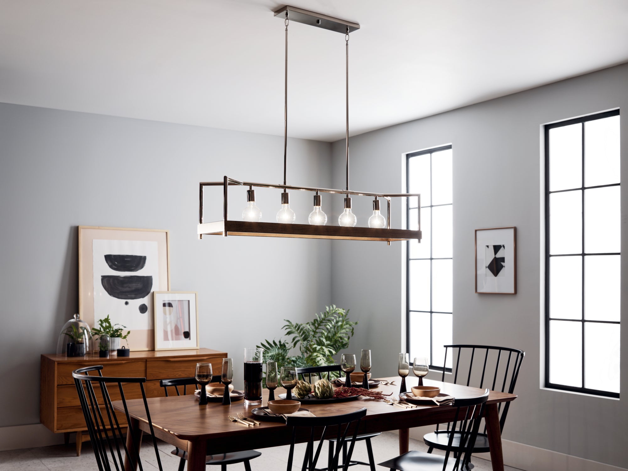 Effortless Hosting Tips for Any Occasion - A sleek and modern dining room with a long wooden table, minimalistic black chairs, and a rectangular bronze chandelier that adds a contemporary touch.