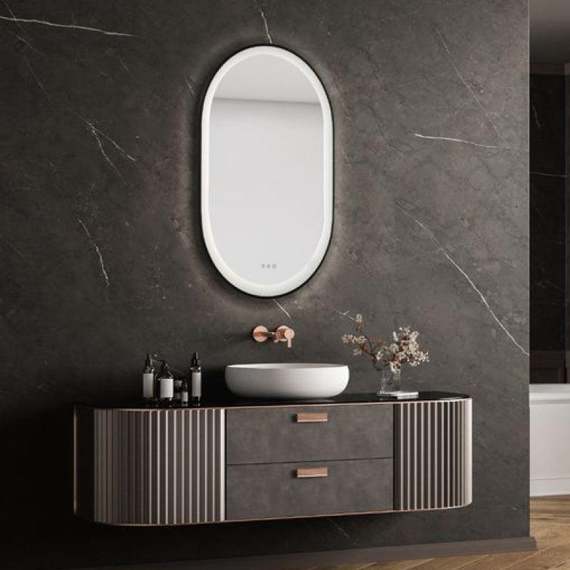 Lighted LED Mirrors oval LED mirror above a modern bathroom vanity with dark stone wall.