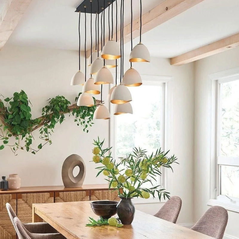 Hinkley multi-light pendant chandelier with white dome shades and gold interiors above a bright dining room table.