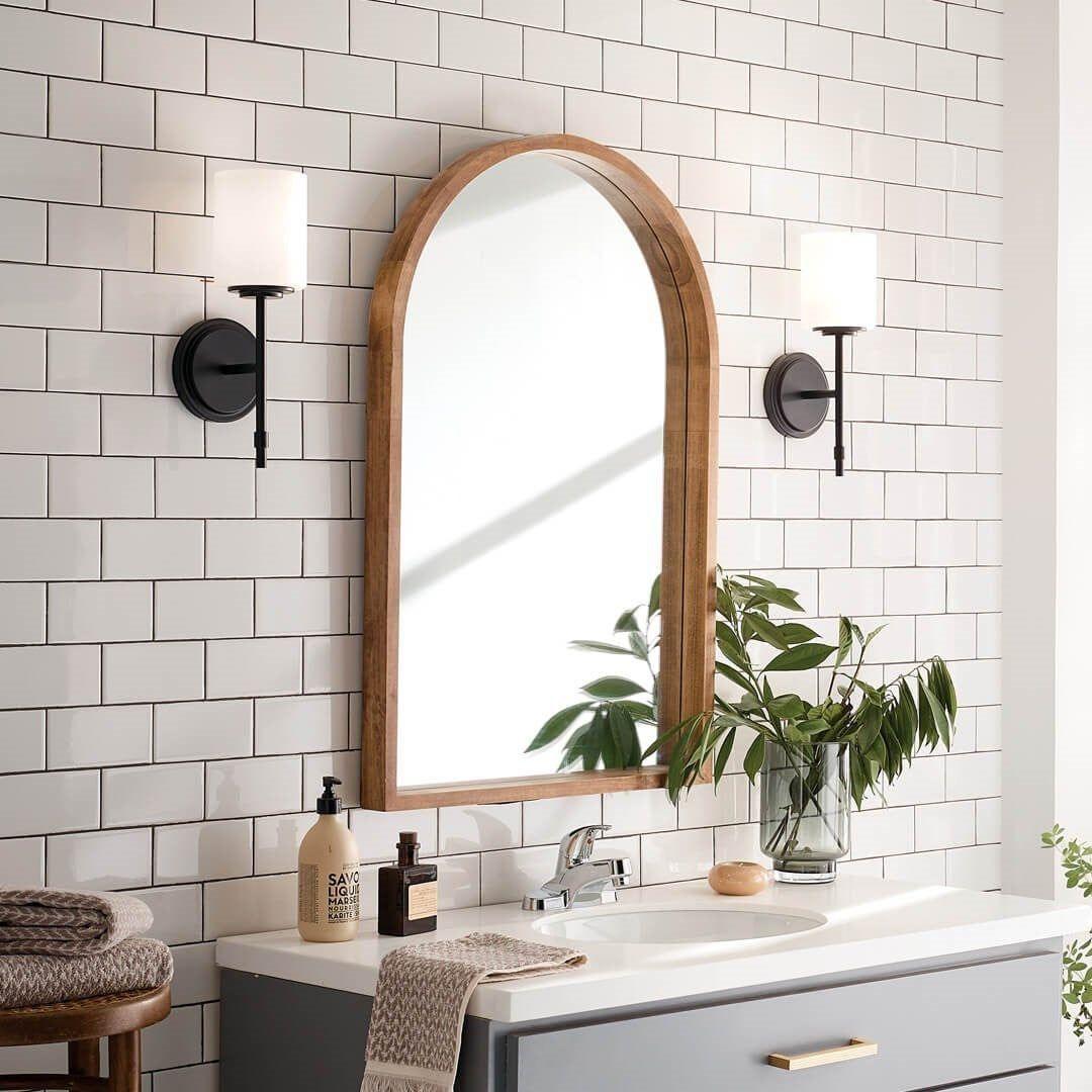 Traditional Sconces black traditional wall sconces with white shades flanking a wood-framed bathroom mirror.