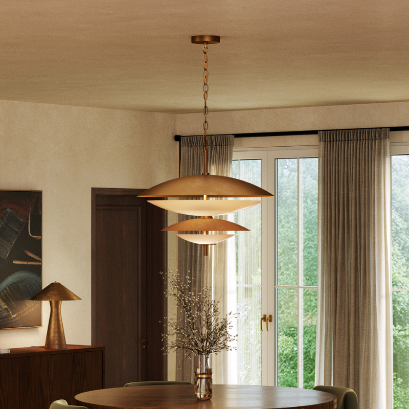 Layered bronze pendant light above a wood dining table in a warm, contemporary dining room.