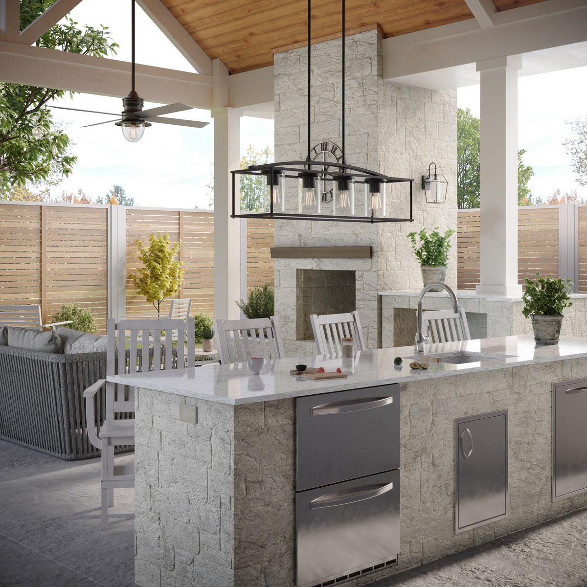 Outdoor chandelier hanging over a kitchen island in a covered patio with a stone fireplace, available at Lights Canada.