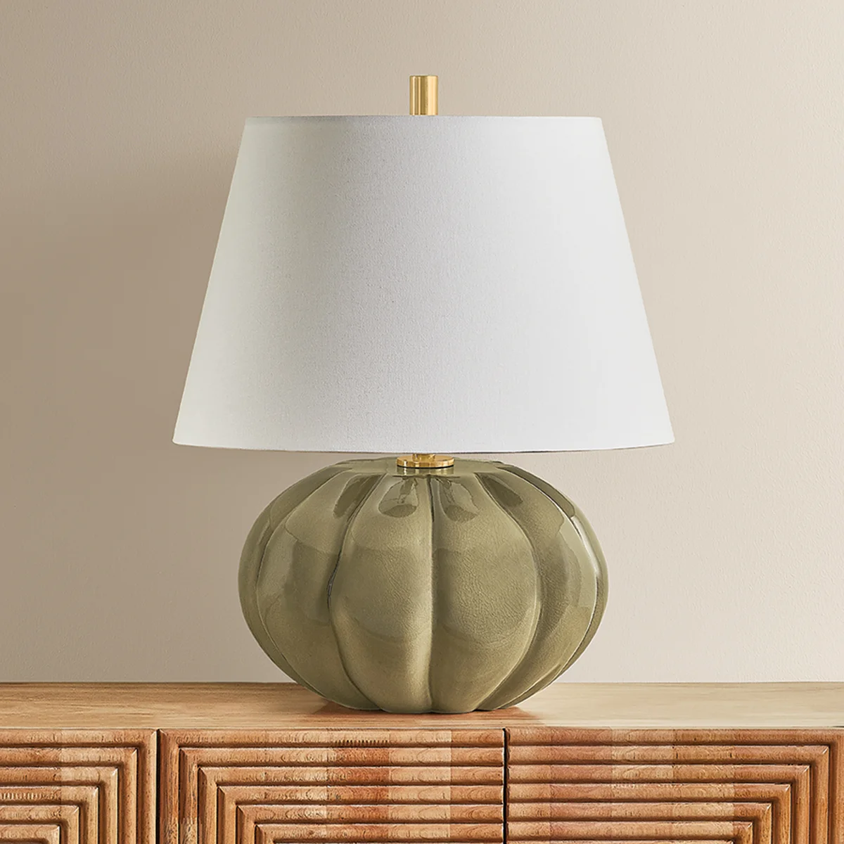 Hudson Valley Lighting Group green ceramic table lamp with a white fabric shade and brass accents on a carved wood console.