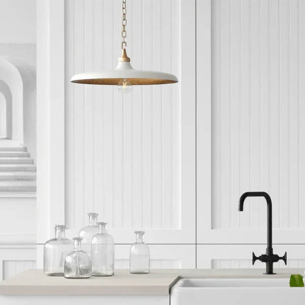 Pendant light from the Visual Comfort Signature Collection hanging over a minimalist countertop with glass bottles.