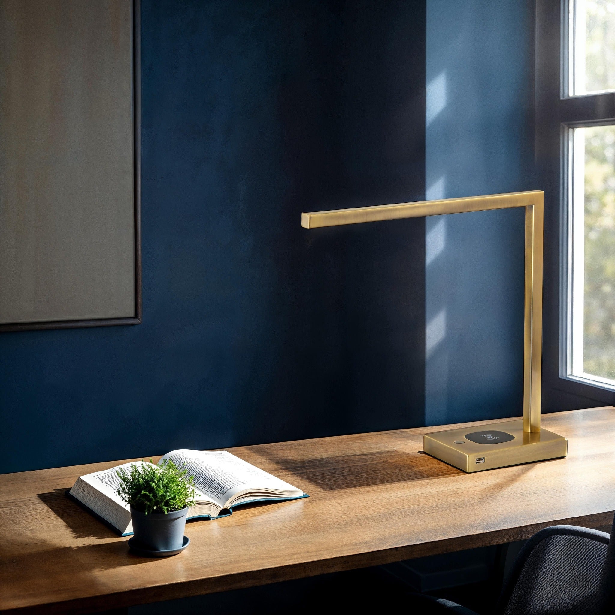 Task Lamp gold LED task lamp on a wooden desk with an open book and small plant.