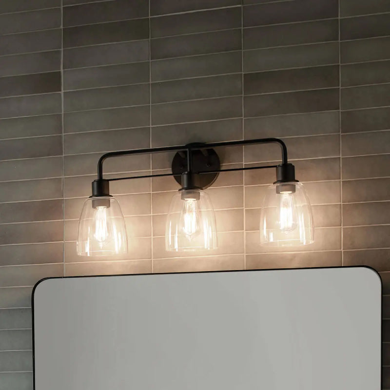 Black Vanity Light 1 black vanity light with clear glass shades mounted above a bathroom mirror.