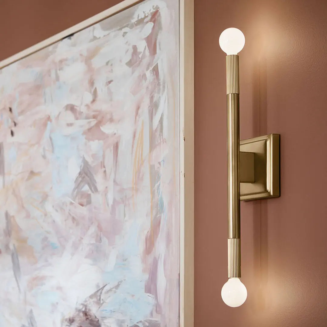 Brass Wall Sconce brass wall sconce with exposed globe bulbs beside framed artwork.