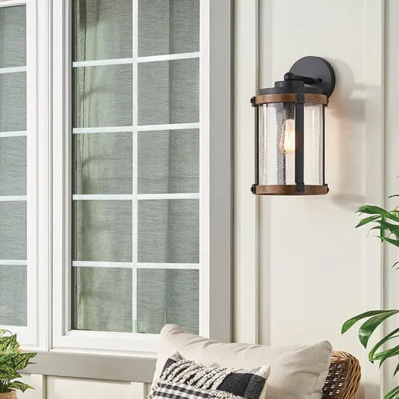 Coastal Outdoor Wall Lights black and bronze outdoor wall light with seeded glass beside a window.