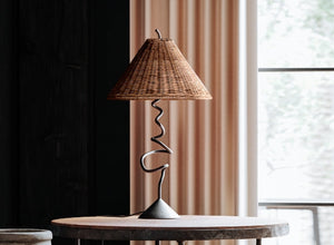 Boho-style table lamp with a twisted metal base and woven rattan shade, creating a cozy and eclectic vibe in a modern interior.