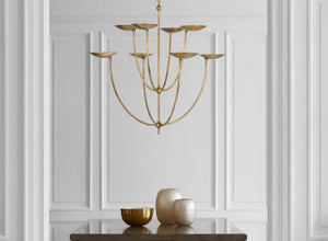 Mediterranean lighting with a gold chandelier featuring sculptural curves, adding elegance to a minimalist, classic interior.