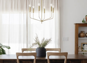 Dining room lighting featuring a modern brass chandelier with exposed bulbs, illuminating a simple and elegant dining space.