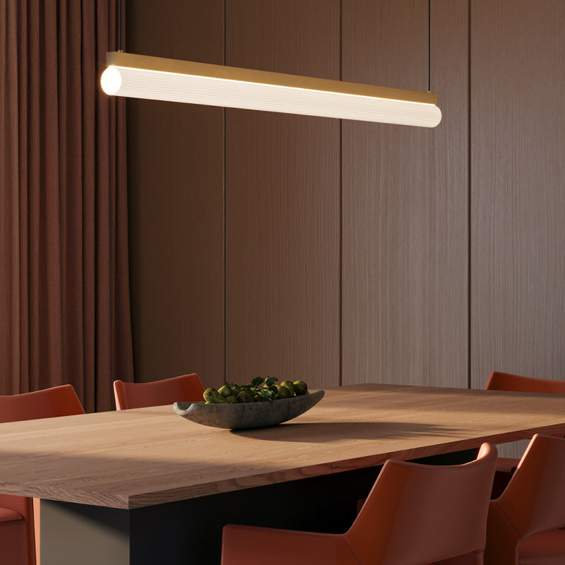 Linear Suspensions ribbed linear suspension light with gold accents above a wooden dining table.
