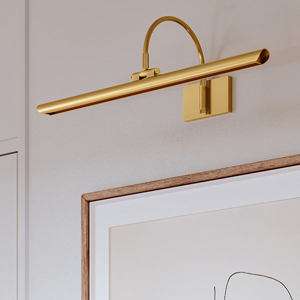Gold picture light mounted above a framed artwork for accent illumination.