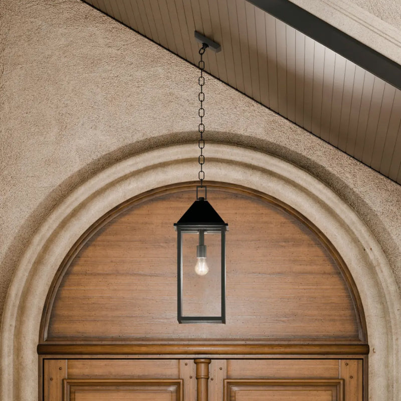 Outdoor Pendant Light black outdoor pendant light hanging above an arched wood entryway.