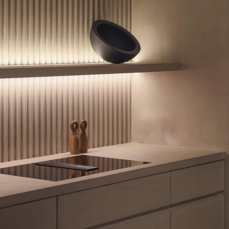 Warm LED tape lighting installed along a modern kitchen shelf and fluted backsplash, creating soft ambient illumination above the countertop.