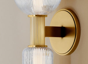 Brass accents featured in a stylish wall sconce with ribbed glass globes, adding elegance to any space.