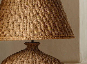 Rattan lighting fixture featuring a textured woven lampshade and a round base, perfect for adding a natural and warm aesthetic to any space.