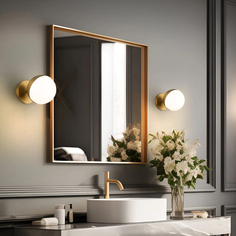 Mid-Century Modern Sconces gold globe wall sconces beside a bathroom mirror.