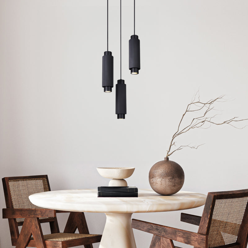 Multi Pendants cluster of black cylinder pendant lights above a round dining table.