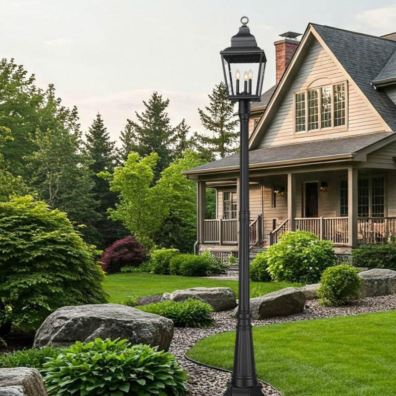 Post Lighting black outdoor post light in a landscaped front yard beside a traditional home.