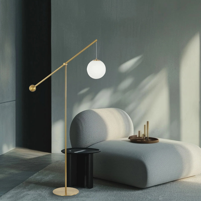 Swing Arm Floor Lamps gold swing arm floor lamp with white globe shade beside a modern lounge chair.