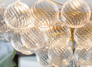 Chandelier featuring textured glass globes with intricate patterns, elegantly reflecting light and adding a touch of sophistication to any interior.