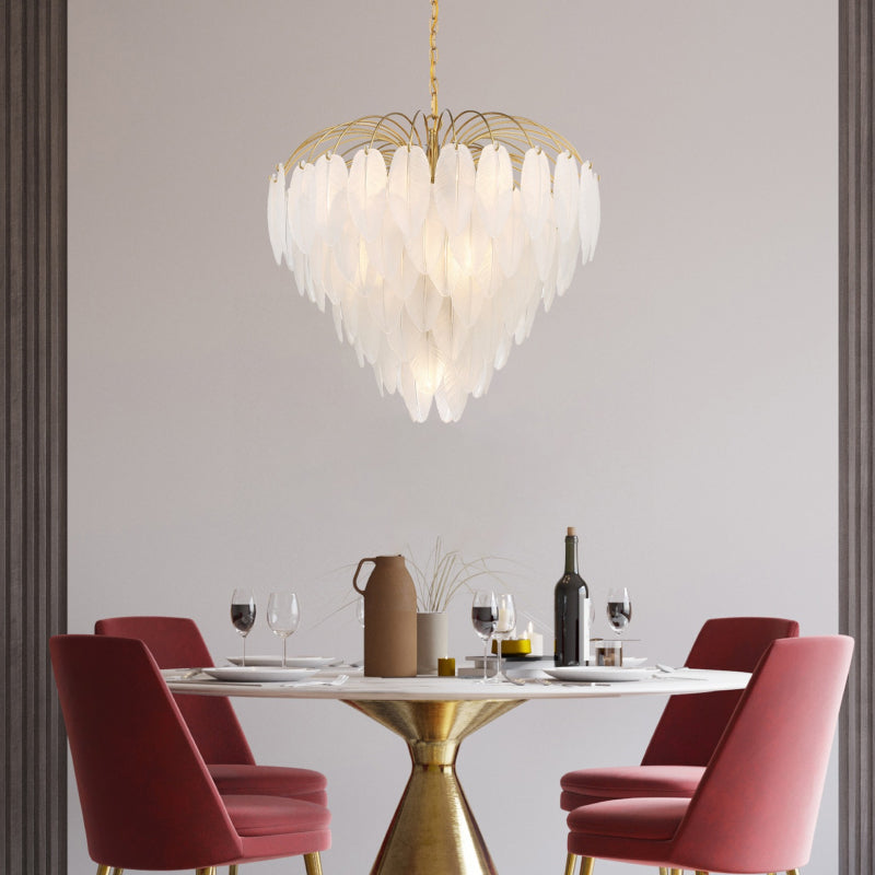 Tiered Chandeliers gold tiered chandelier with layered white glass petals above a modern dining table.