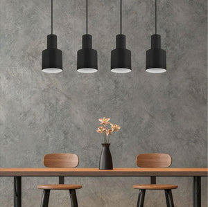 Set of black pendant lights by Trio Lighting hanging above a modern dining table at Lights Canada