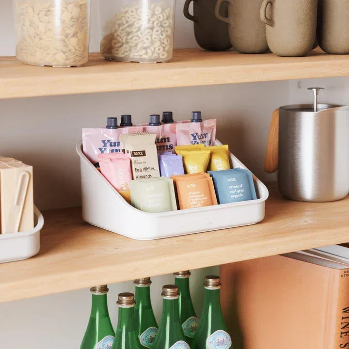 Umbra organizer on a kitchen shelf, neatly holding snack bars and pouches in a modern pantry setting.