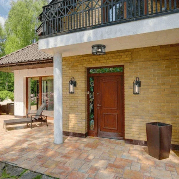 Outdoor wall and ceiling lights illuminating the entrance of a home with brick walls and a wooden door.