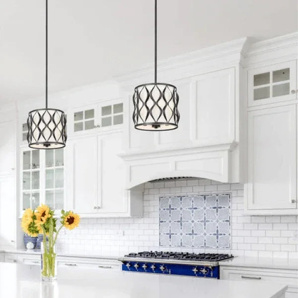 Two pendant lights hanging over a kitchen island with white cabinetry and a sunflower bouquet on the counter.