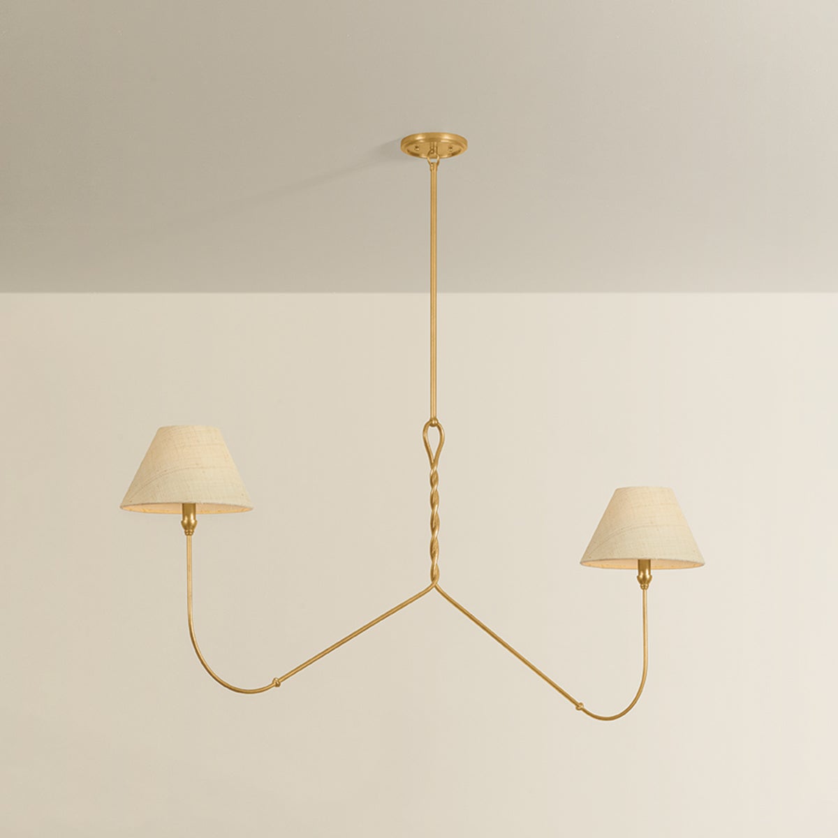 Two-arm chandelier with twisted gold brass stem and two curved arms each holding a cream drum shade