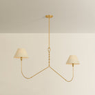 Two-arm chandelier with twisted gold brass stem and two curved arms each holding a cream drum shade
