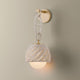 Piasu wall sconce illuminated, woven rattan shade glowing warm on gold brass chain link bracket with globe light below