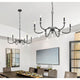 Two black iron chandeliers with candle-style bulbs above a modern dining table