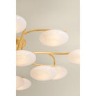 Close-up view from below of multi-arm chandelier with oval white glass globes on gold brass arms