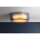 Gunmetal grey round flush mount ceiling light illuminated, showing warm amber glow through diffuser