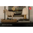 Decorative items on a shelf including a horse figurine, lamp, and books with a visible brand logo.