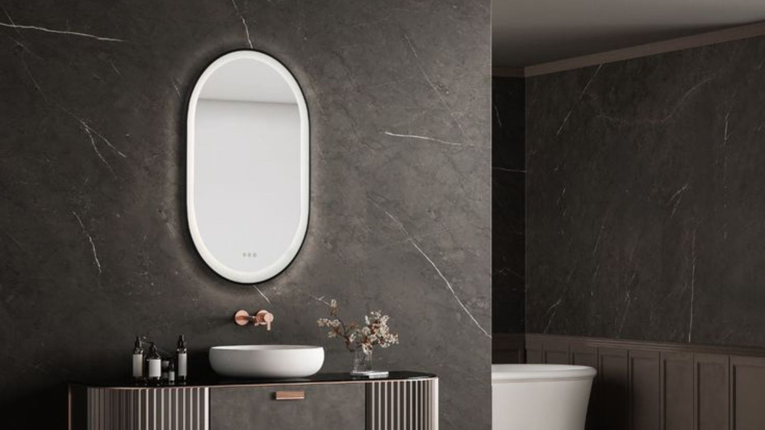 Oval backlit LED bathroom mirror with touch controls above vessel sink on fluted vanity against dark veined marble wall