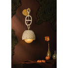 Piasu woven rattan wall sconce in dark moody styled scene with moss wall, flowers and decorative objects