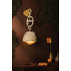 Piasu woven rattan wall sconce in dark moody styled scene with moss wall, flowers and decorative objects