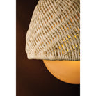 Close-up detail of Piasu wall sconce woven rattan shade showing intricate woven texture with warm amber glow from within