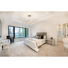 Gold-toned ring chandelier with sparkling clear accents above a bed in a bright white bedroom.