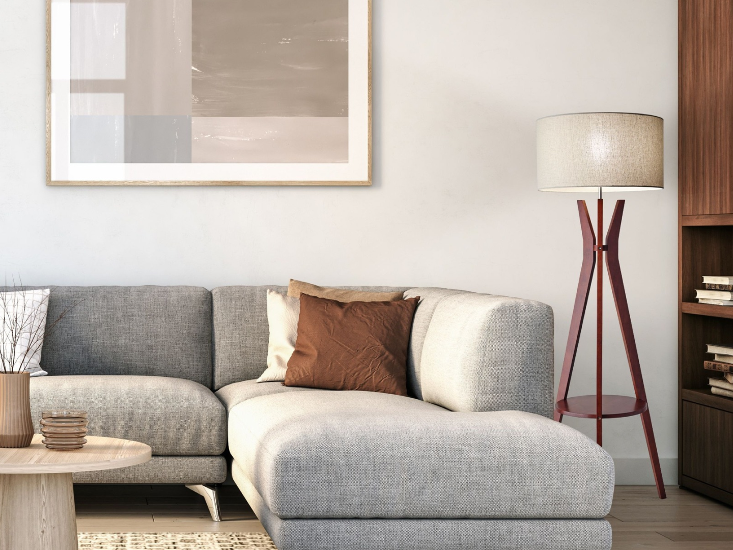 Mid-century walnut tripod floor lamp with linen drum shade beside grey sectional sofa in warm neutral living room