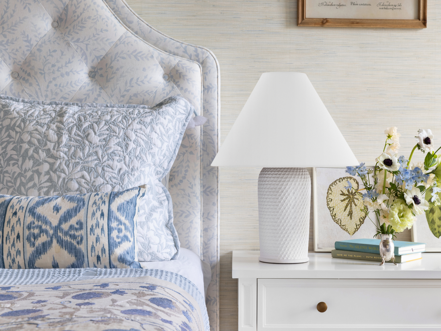 White textured ceramic table lamp with tapered shade on white nightstand in soft blue and white coastal bedroom